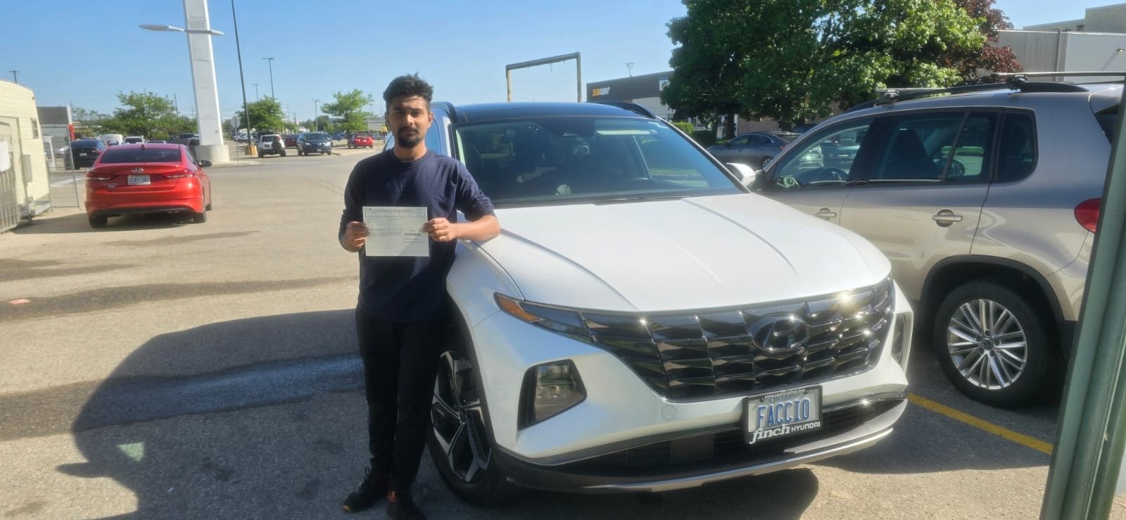 Student celebrating a driving milestone beside a white Educator Driving School vehicle