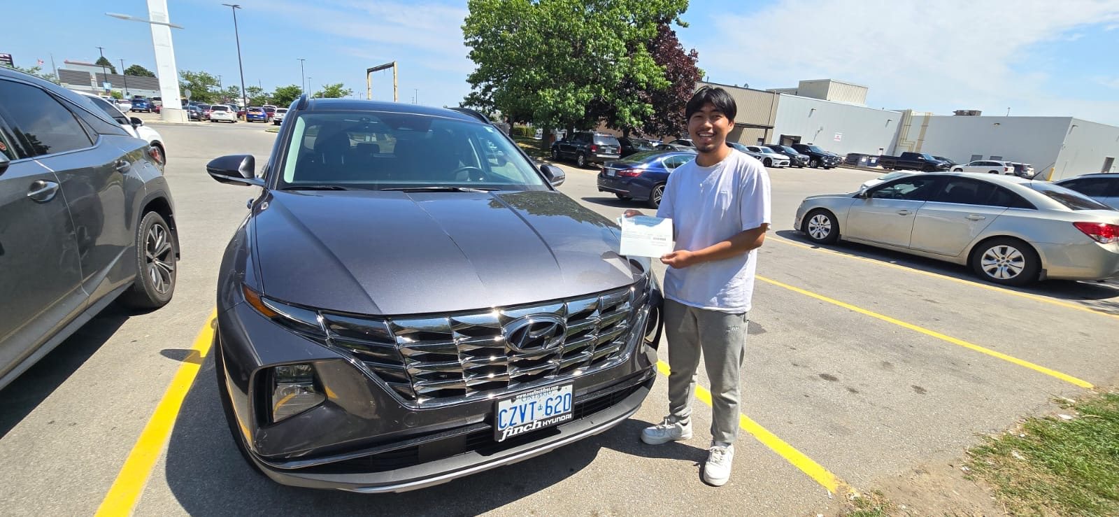Student holding a road-test result beside a driving-school vehicle